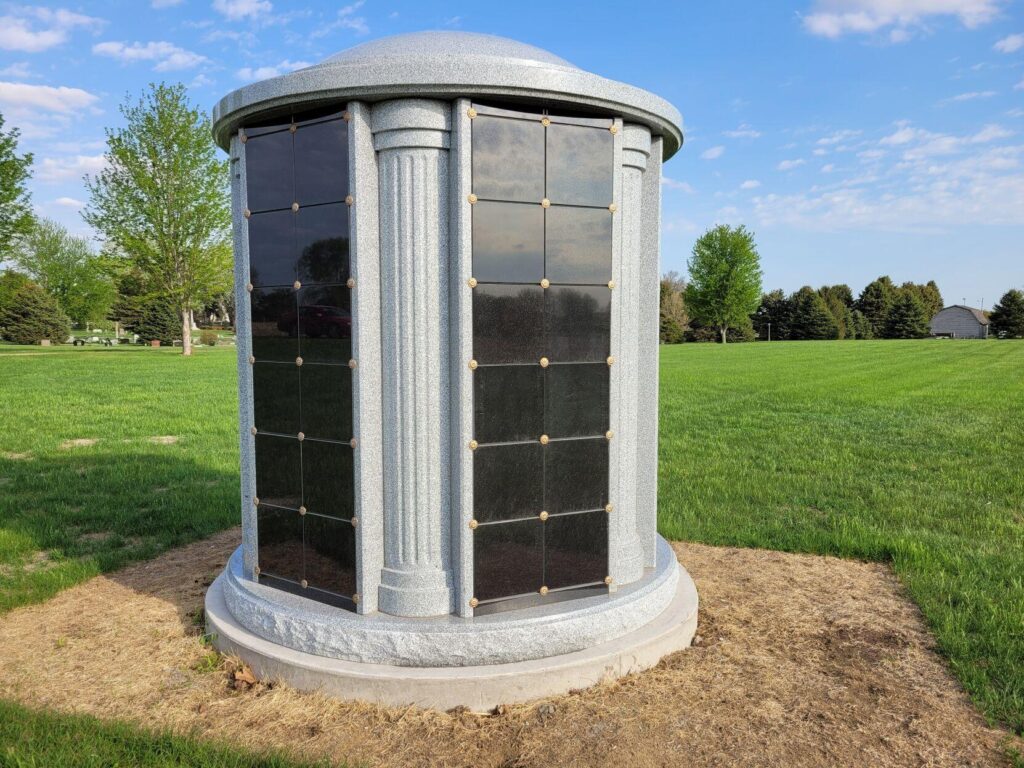 A columbarium at Grace Hill Cemetery, featuring a granite structure with niches for storing cremation urns, set in a peaceful green cemetery landscape.